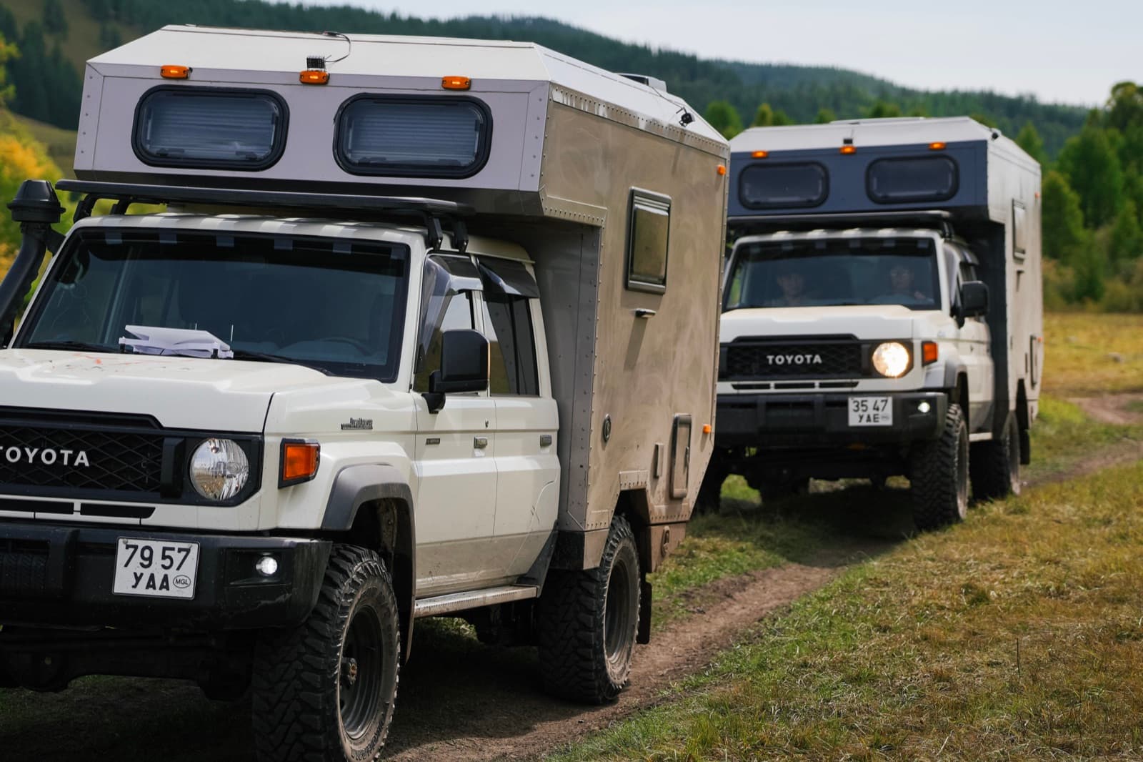 Two Toyota expedition vehicles on a forest trail in Mongolia