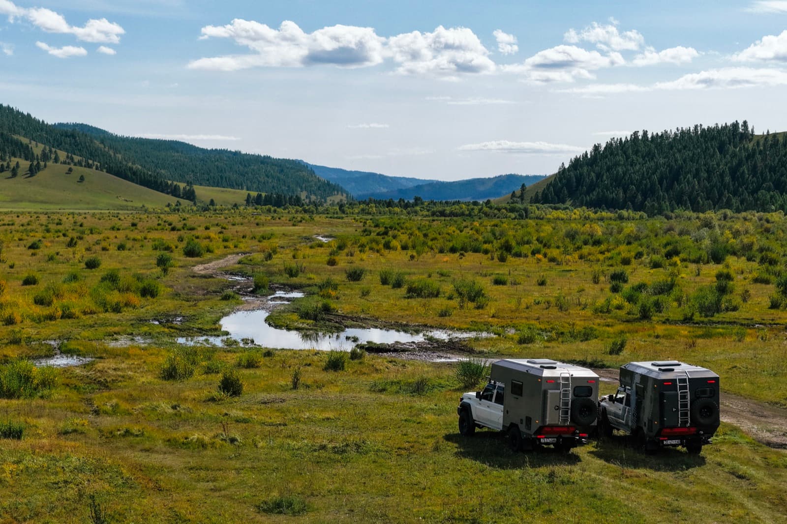 Two expedition vehicles beside a mountain valley in Mongolia